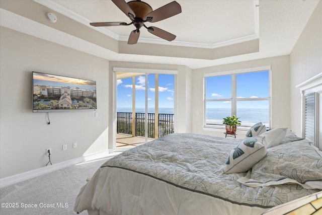 carpeted bedroom featuring access to exterior, a tray ceiling, and ornamental molding