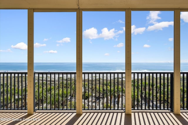 unfurnished sunroom featuring a water view and a beach view