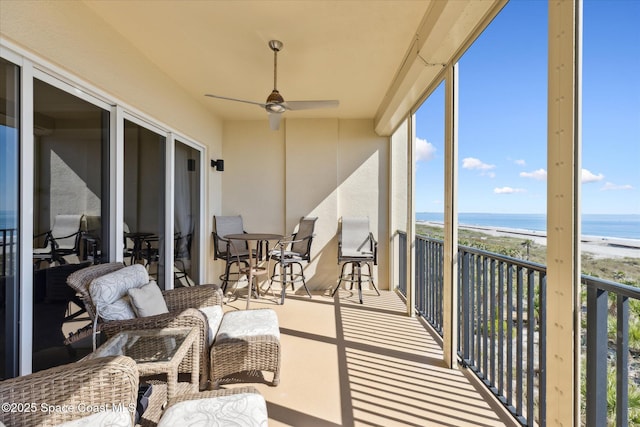 sunroom / solarium featuring a beach view, ceiling fan, and a water view