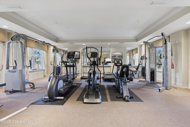 gym with a tray ceiling, visible vents, and crown molding