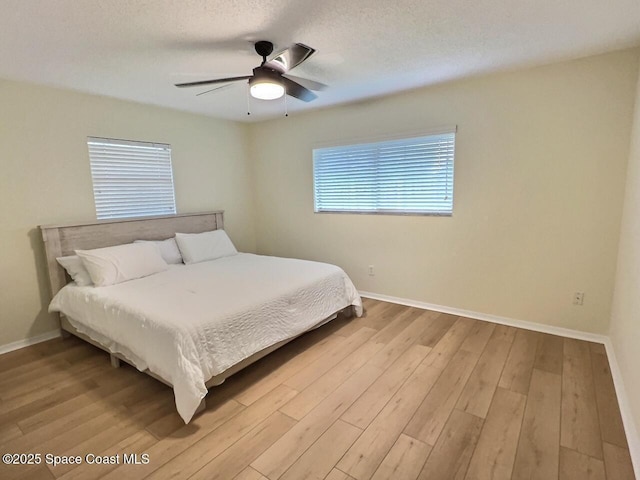 bedroom with a textured ceiling, a ceiling fan, light wood-style flooring, and baseboards