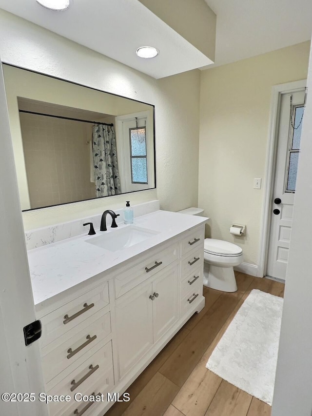 bathroom with toilet, a shower with curtain, wood finished floors, and vanity