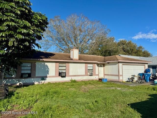 rear view of property featuring a garage and a yard