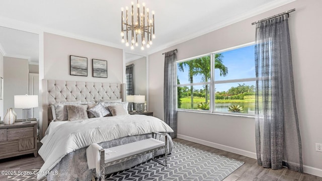 bedroom featuring crown molding, a water view, wood finished floors, a chandelier, and baseboards