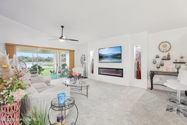 living area featuring vaulted ceiling, carpet floors, ceiling fan, and a glass covered fireplace