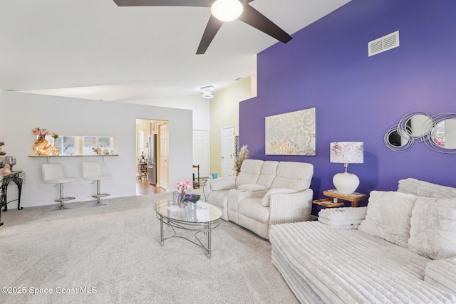 carpeted living area with lofted ceiling, visible vents, and a ceiling fan