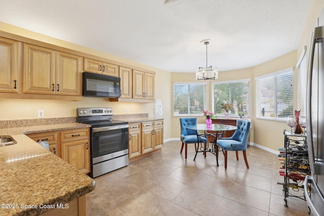 kitchen with light stone counters, a notable chandelier, stainless steel appliances, hanging light fixtures, and light tile patterned flooring