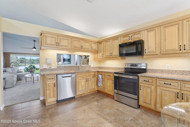 kitchen featuring light stone counters, stainless steel appliances, lofted ceiling, light brown cabinetry, and a sink