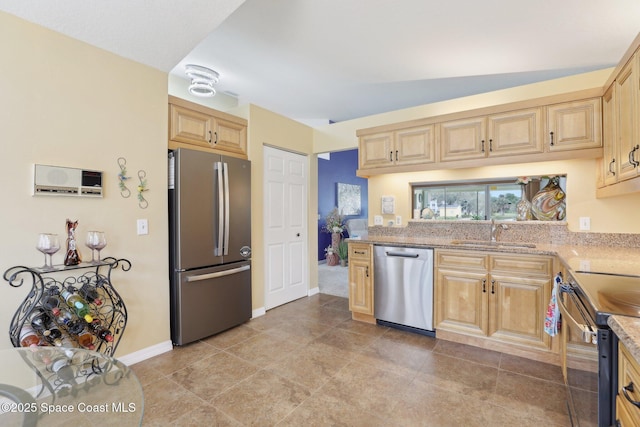 kitchen featuring light stone countertops, light brown cabinets, appliances with stainless steel finishes, and a sink