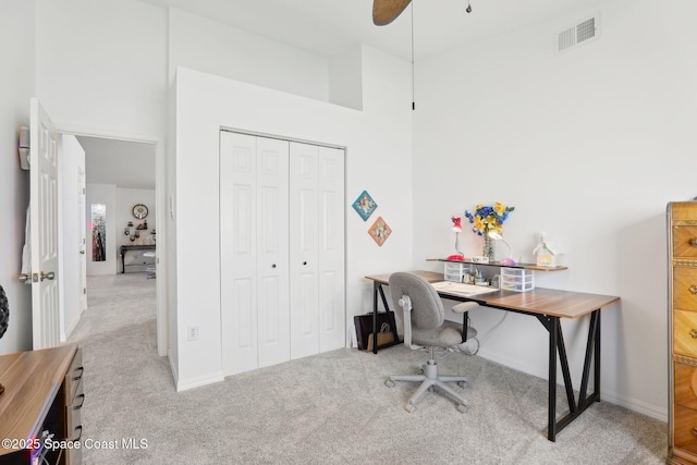 office area featuring baseboards, visible vents, a towering ceiling, and carpet flooring