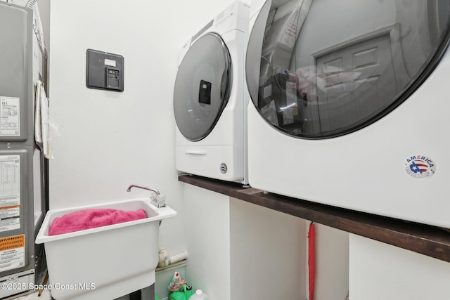 laundry area with laundry area, a sink, and washing machine and clothes dryer