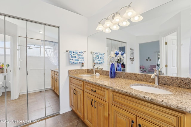 ensuite bathroom with tile patterned flooring, a sink, toilet, and double vanity