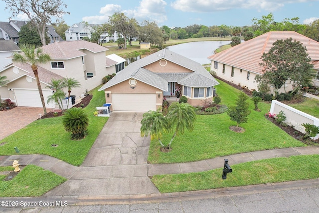 view of front facade with concrete driveway, a water view, fence, a front lawn, and stucco siding