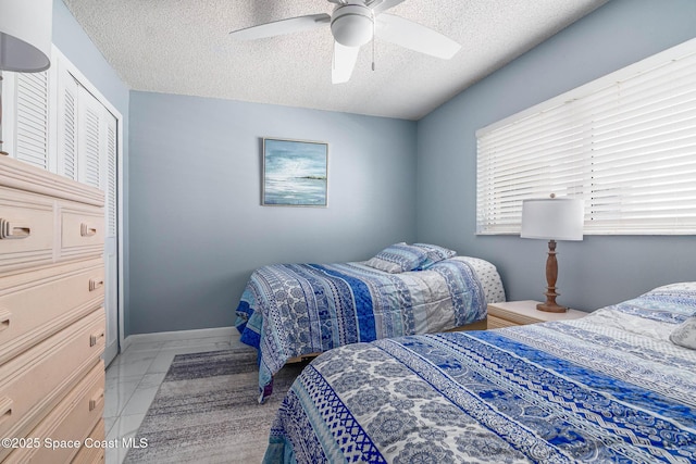 bedroom with a textured ceiling, marble finish floor, a ceiling fan, and baseboards