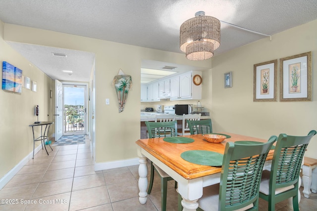 dining room with a textured ceiling, light tile patterned flooring, a chandelier, and baseboards