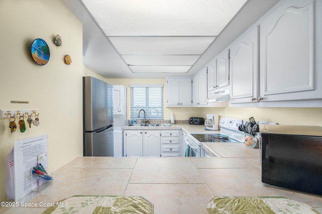 kitchen featuring white cabinets, electric stove, freestanding refrigerator, extractor fan, and a sink