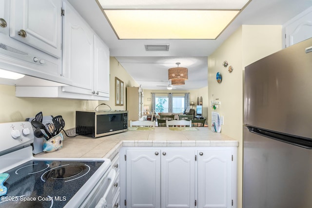 kitchen featuring stainless steel appliances, visible vents, a ceiling fan, white cabinetry, and a peninsula