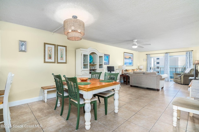 dining area with light tile patterned floors, a textured ceiling, ceiling fan with notable chandelier, and baseboards