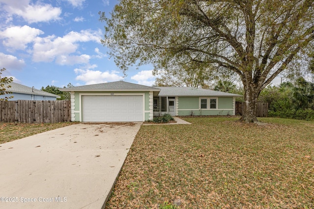 ranch-style home featuring a garage, driveway, fence, and a front yard