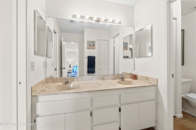 full bath with tile patterned flooring, a sink, toilet, and double vanity