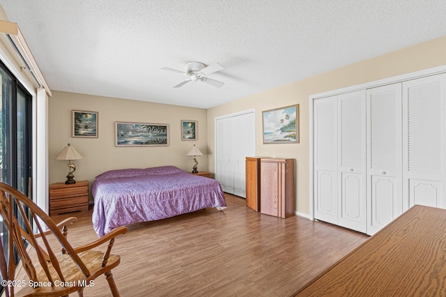 bedroom featuring a textured ceiling, wood finished floors, a ceiling fan, and multiple closets