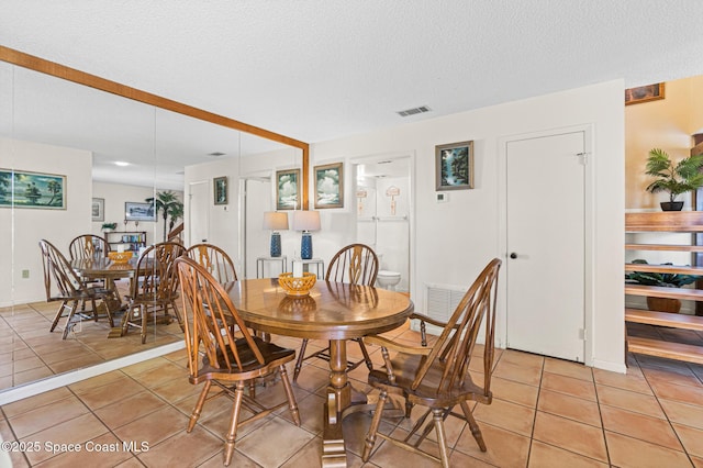 dining area featuring visible vents, light tile patterned floors, a textured ceiling, and stairs