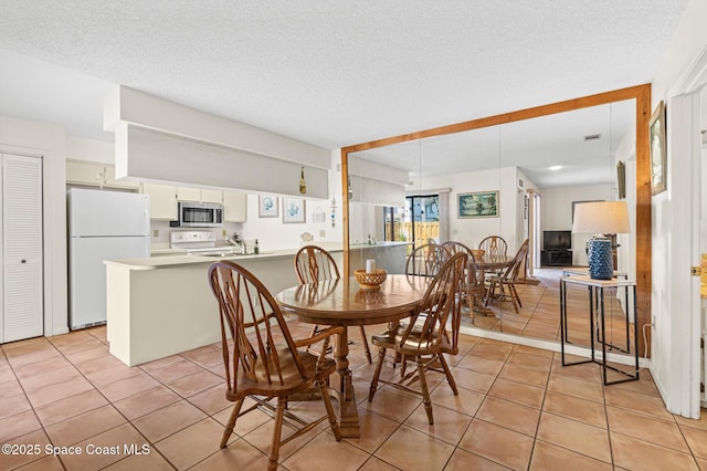 dining area with light tile patterned flooring and a textured ceiling