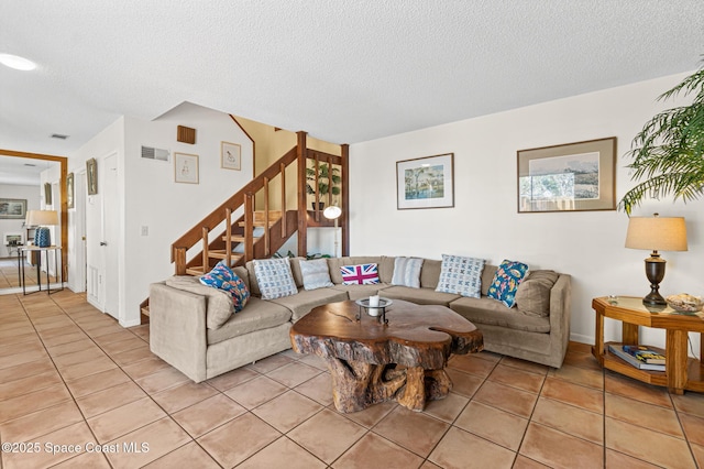 living area featuring light tile patterned floors, stairway, a textured ceiling, and visible vents