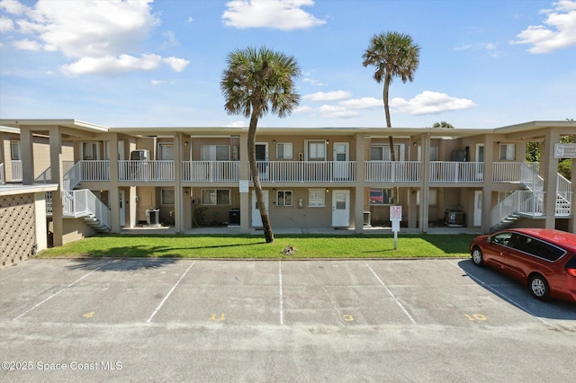 view of property featuring uncovered parking, stairway, and cooling unit