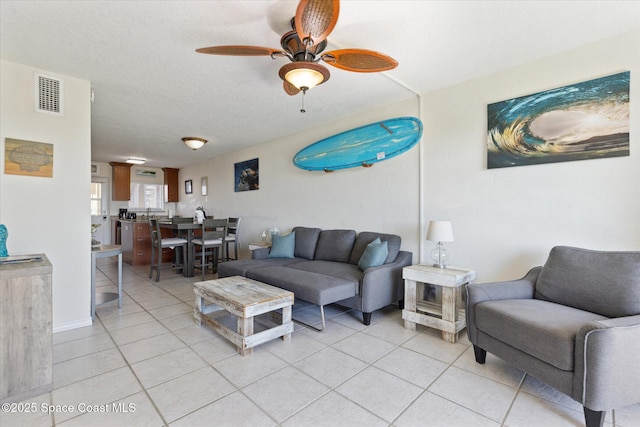 living area featuring a textured ceiling, ceiling fan, light tile patterned flooring, and visible vents