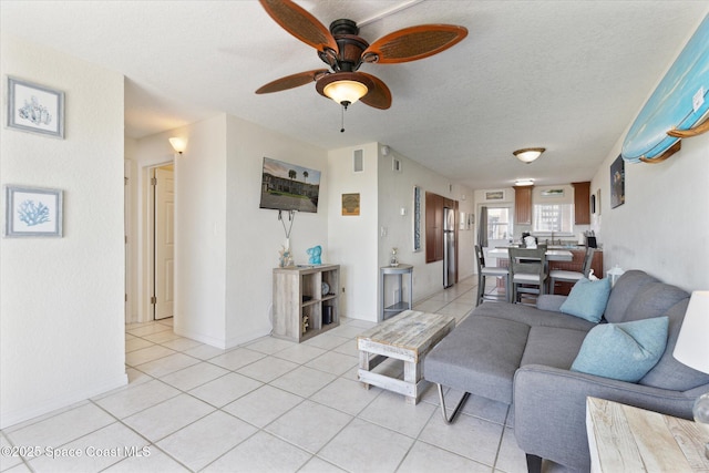 living area with light tile patterned floors, a textured ceiling, visible vents, and a ceiling fan