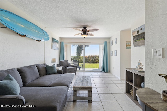 living area featuring light tile patterned floors, ceiling fan, a textured ceiling, and a textured wall