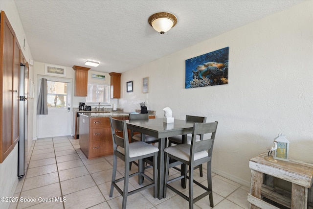 dining room featuring light tile patterned flooring, a textured ceiling, and baseboards