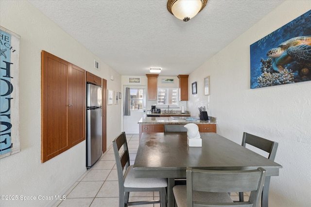 dining area with light tile patterned floors, a textured ceiling, and visible vents