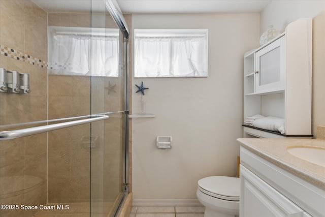 bathroom with toilet, vanity, baseboards, tile patterned floors, and a stall shower