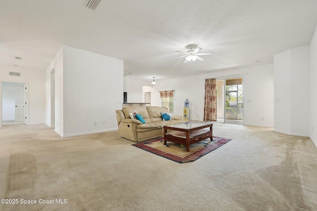 living room featuring a ceiling fan, visible vents, and light carpet