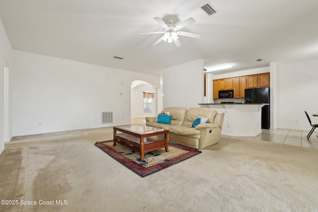 living room with visible vents, light carpet, arched walkways, and ceiling fan