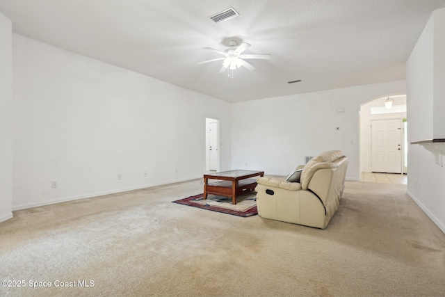 living room with light carpet, visible vents, arched walkways, and ceiling fan