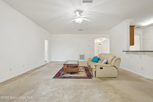 living area featuring arched walkways, visible vents, carpet flooring, and a ceiling fan