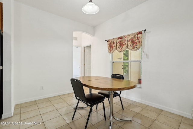 dining space featuring visible vents, light tile patterned floors, baseboards, and arched walkways