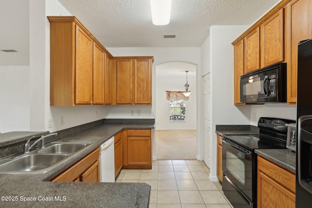 kitchen with visible vents, black appliances, a sink, dark countertops, and arched walkways