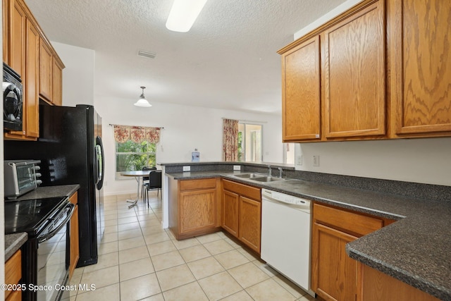 kitchen featuring light tile patterned floors, brown cabinetry, a sink, black appliances, and dark countertops