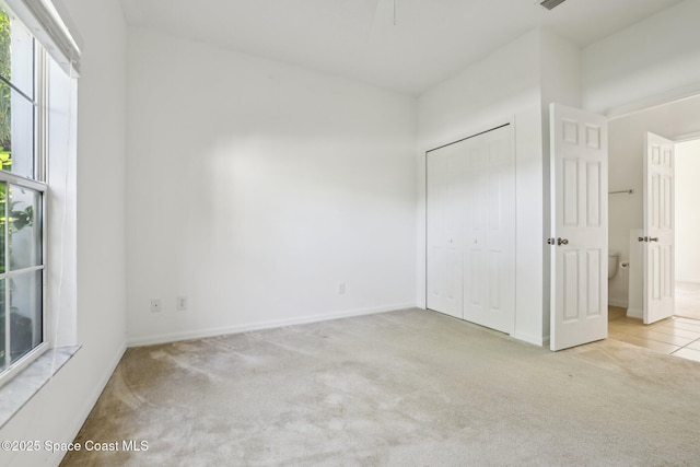 unfurnished bedroom with a closet, tile patterned flooring, baseboards, and carpet floors