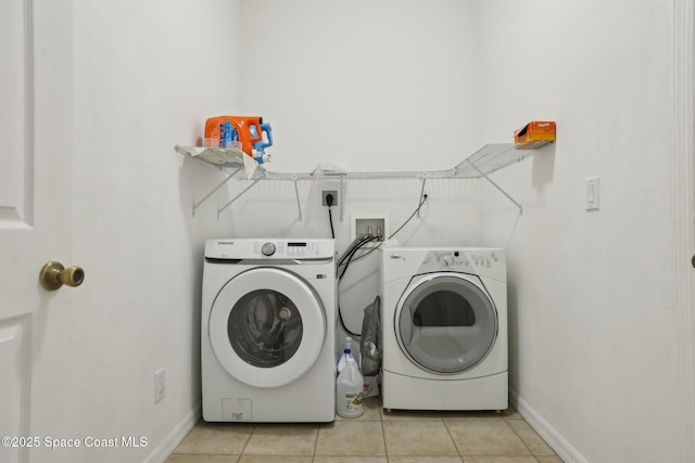 laundry room with light tile patterned floors, laundry area, washer and dryer, and baseboards