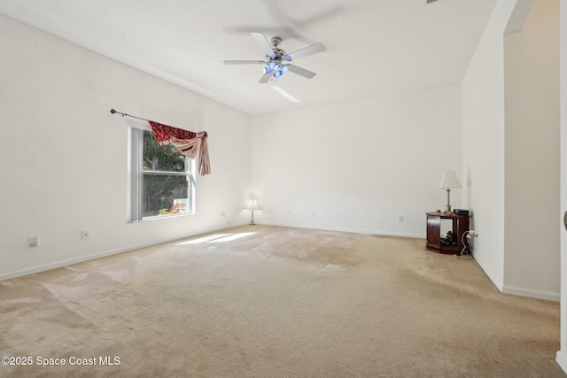 empty room featuring a ceiling fan, baseboards, and light carpet