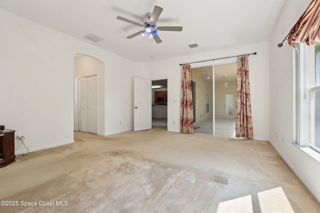 unfurnished bedroom with arched walkways, carpet flooring, baseboards, and visible vents