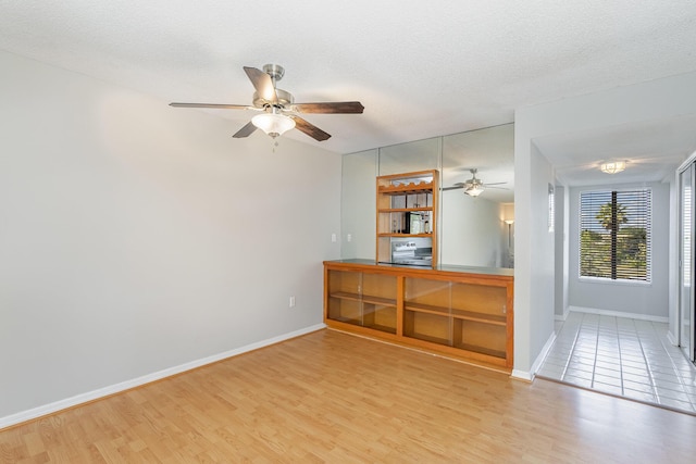 empty room featuring a textured ceiling, baseboards, and wood finished floors