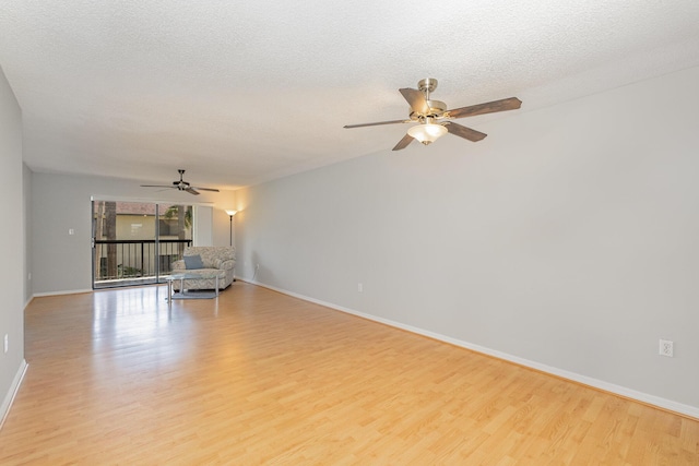 unfurnished living room with light wood-style flooring, baseboards, ceiling fan, and a textured ceiling