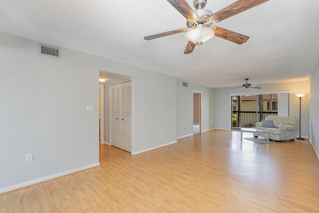 unfurnished living room featuring ceiling fan, a textured ceiling, light wood-style flooring, visible vents, and baseboards