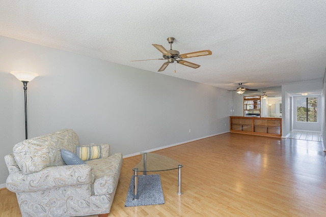 living room with a textured ceiling, wood finished floors, and baseboards